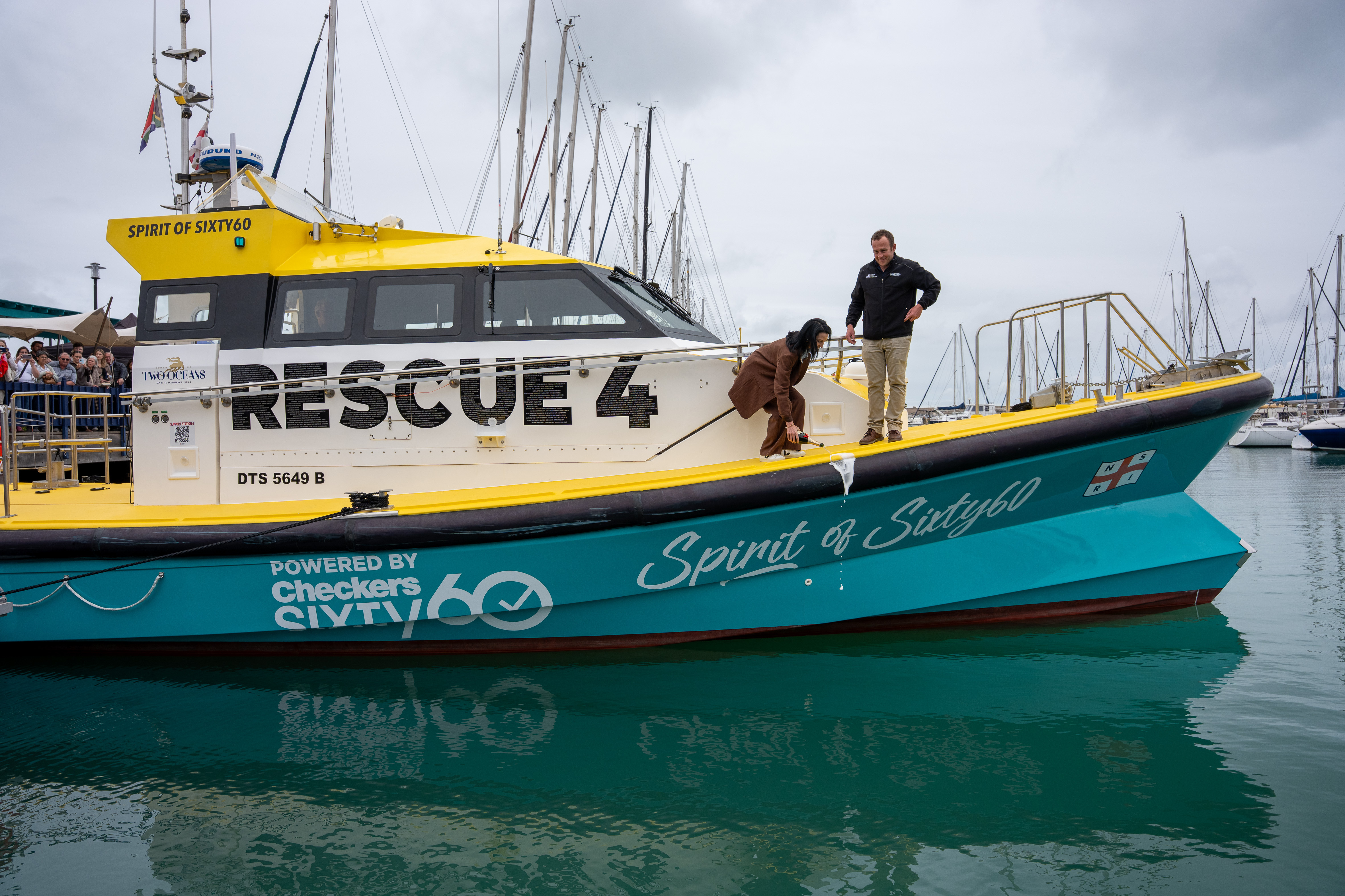 Ilze Bylos, Chief Marketing Officer of the Shoprite Group names the vessel watched by NSRI Mykonos Station Commander Nic Stevens.     Celebrating lives and saving lives as NSRI names Rescue 4 at Mykonos
Personal tributes and a new Shoprite Group sponsorship support lifesaving work on the West Coast

A gift celebrating a couple’s wedding anniversary. A tribute to a mother who quietly supported sea rescue. A husband’s thank you to the wife who helped him through recovery.

These are some of the stories carried by Rescue 4, the National Sea Rescue Institute’s (NSRI) new Offshore Rescue Craft, blessed and named at Club Mykonos, Langebaan, on Saturday 17 October.

Families, donors and volunteers came together to celebrate the vessel, which serves Station 4 Mykonos and the West Coast. Within her RESCUE lettering are the names of loved ones honoured through the NSRI’s Celebrate a Life campaign. Donations made in their honour helped fund her construction.

The vessel was named Spirit of Shoprite Sixty60, recognising a new sponsorship from the Shoprite Group supporting Rescue 4 and the NSRI’s lifesaving work.

For NSRI Chief Executive Officer Mike Vonk, the occasion reflected the many relationships that sustain the organisation.
 Picture Andrew Ingram / NSRI